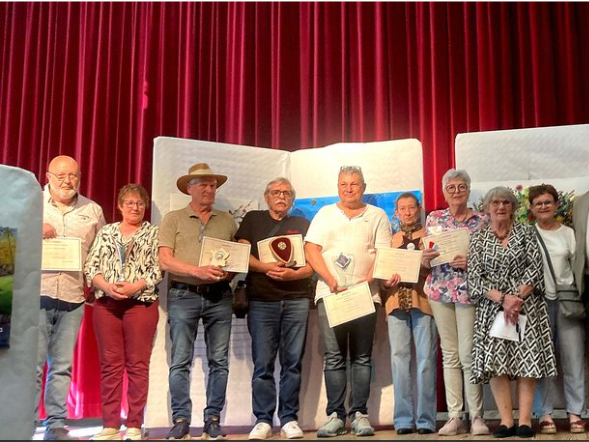 Groupe de personnes sur scène, recevant des prix, devant un fond rouge et blanc.